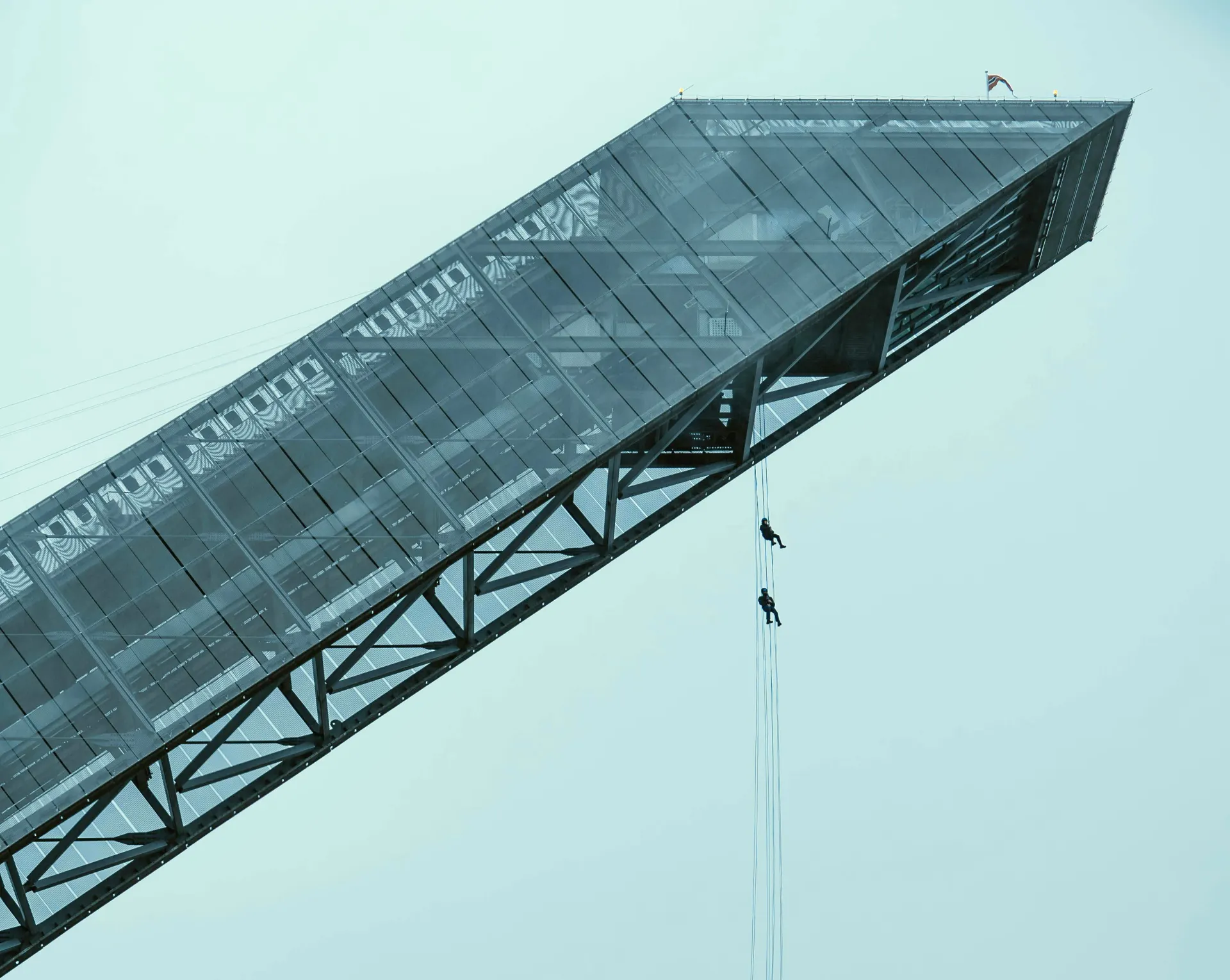 Rope access technicians abseiling from a high steel structure